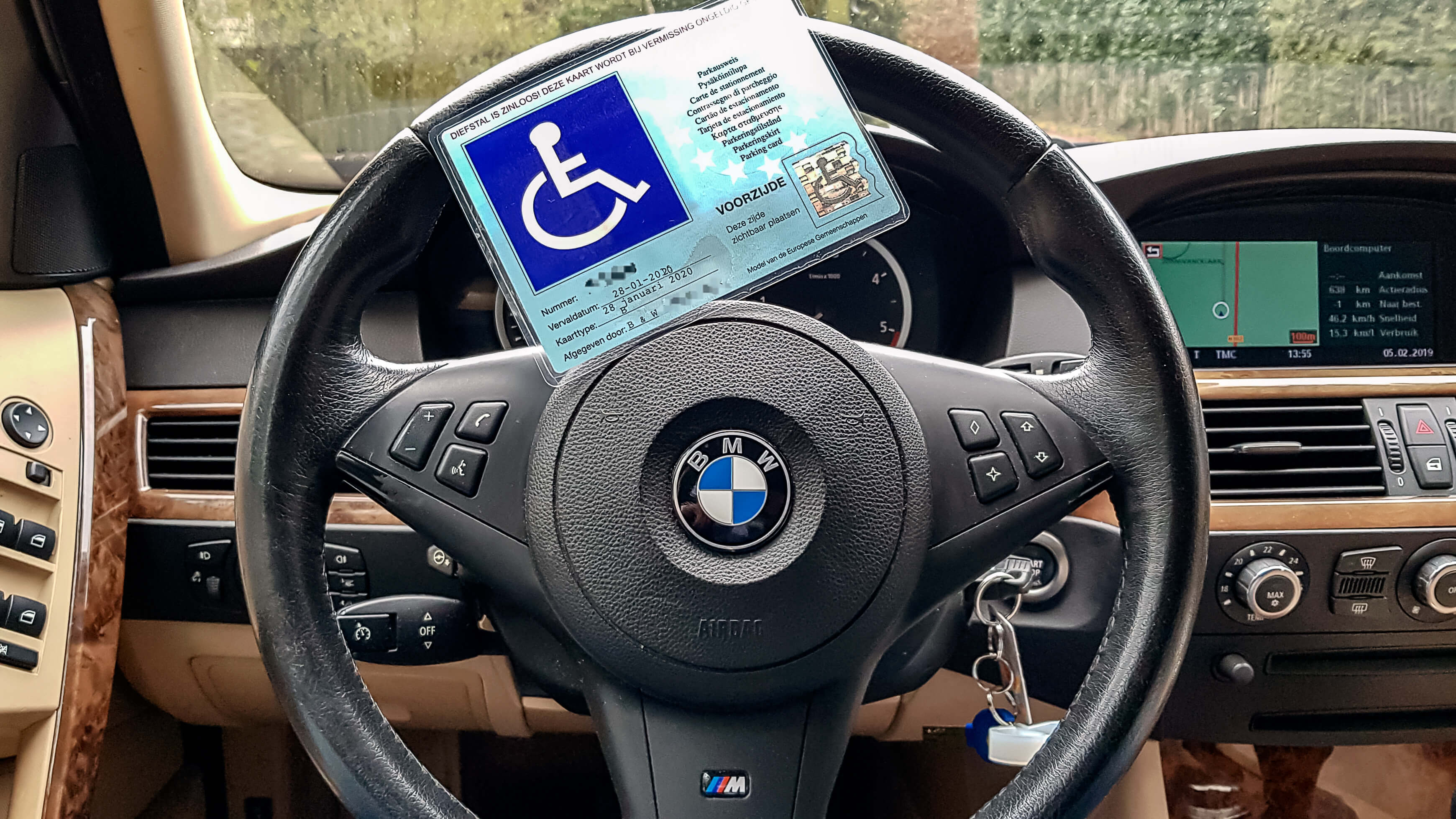 Afbeelding van gehandicaptenparkeerkaart vanwege ziekte van bechterew reuma op het stuur van een BMW 5-serie