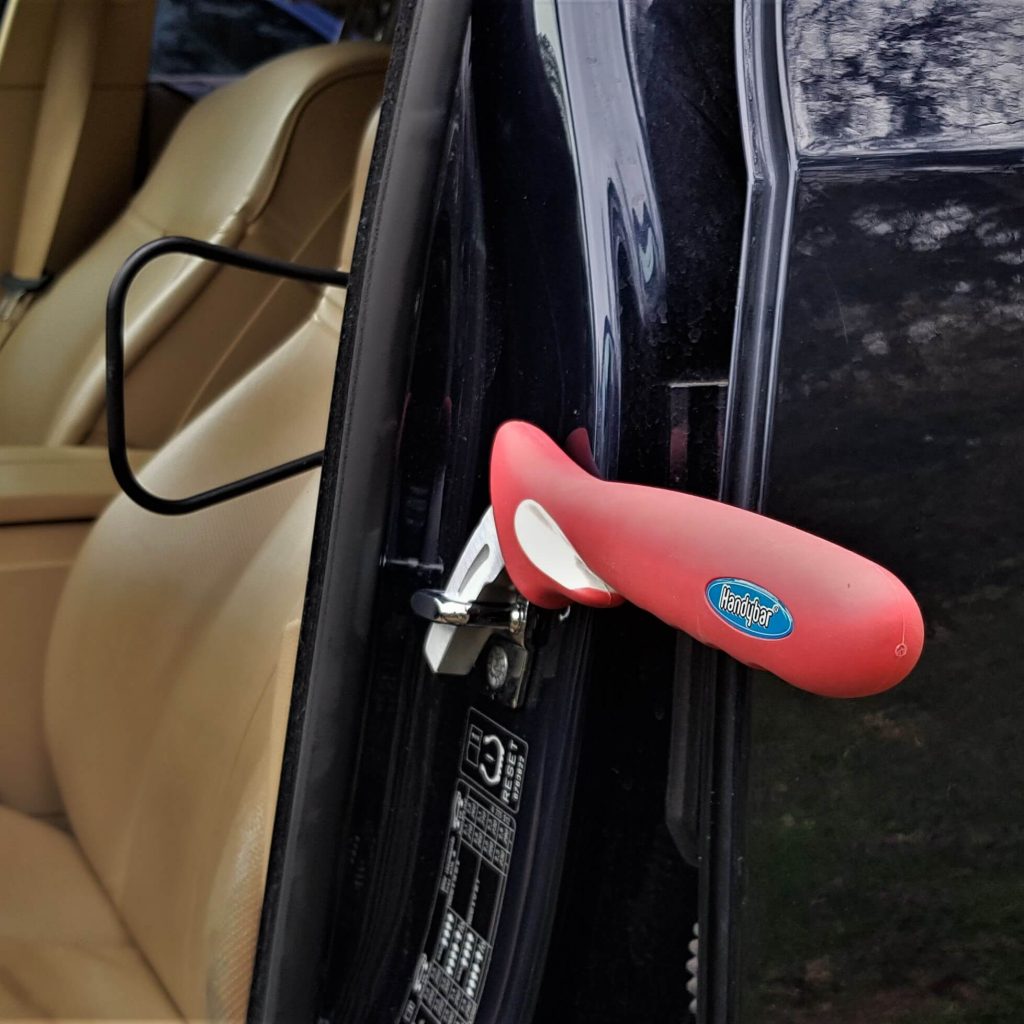De handybar hulpmiddel voor in- en uitstappen van de auto hang je in de slotvanger van de autodeur