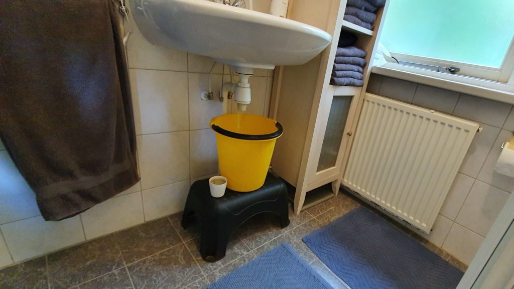 Water spoelt via de sifon in de emmer om daarmee het toilet door te kunnen trekken