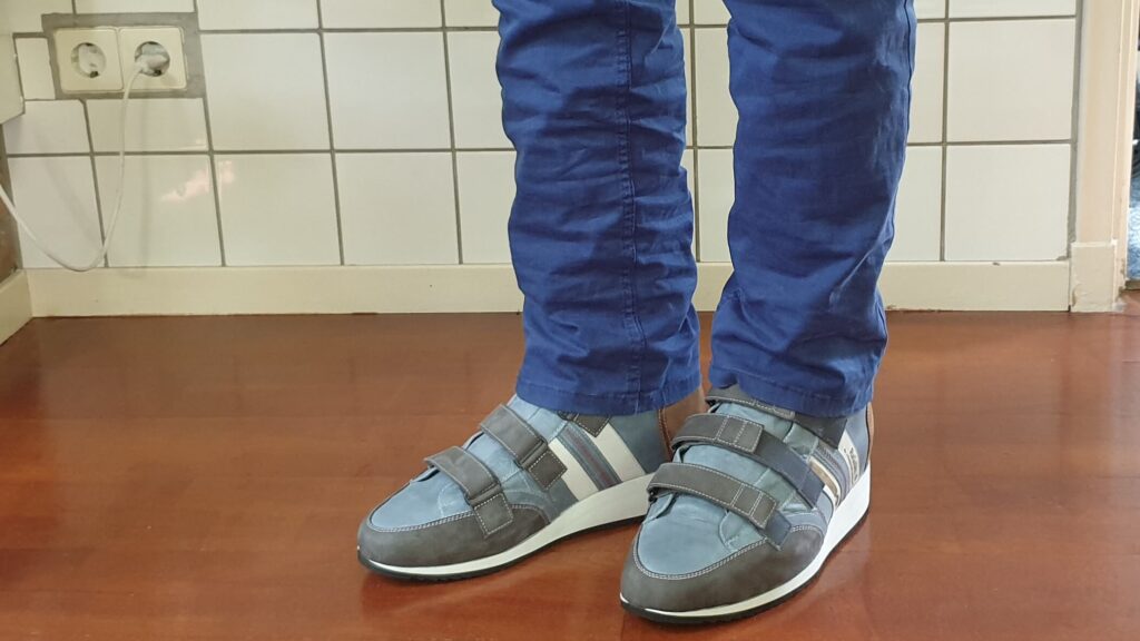 foto van hoge orthopedische schoenen met klittenband onder een blauwe broek met op de zijkant het logo van RaGaSto