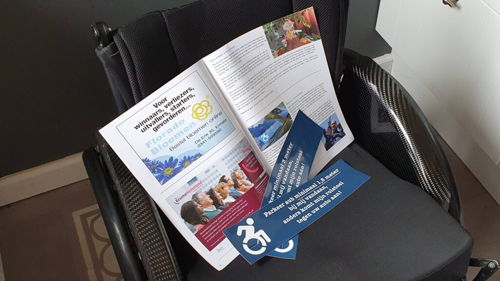 Magazine De Sprong van RPV Randmeren op een TNS rolstoel met rolstoelstickers voor op de auto
