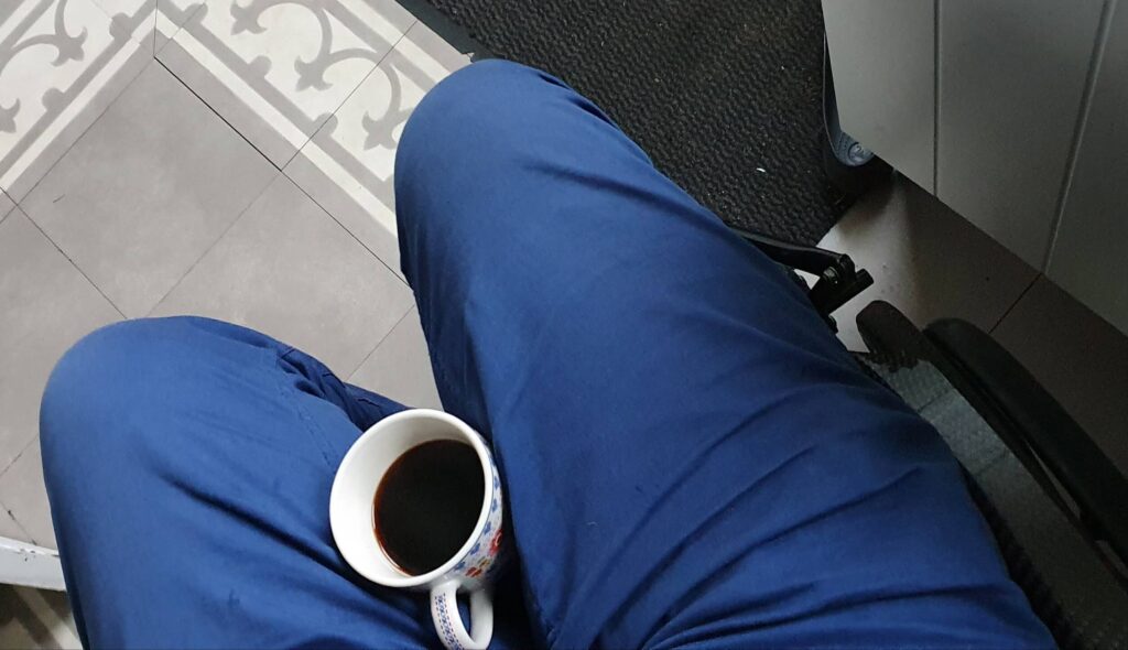Foto van een koffiebeker met hete koffie in de schoot van iemand in een rolstoel