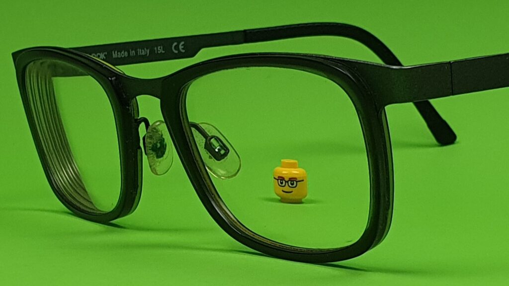 photo taken through a real pair of glasses of a lego head with a print as a glasses user