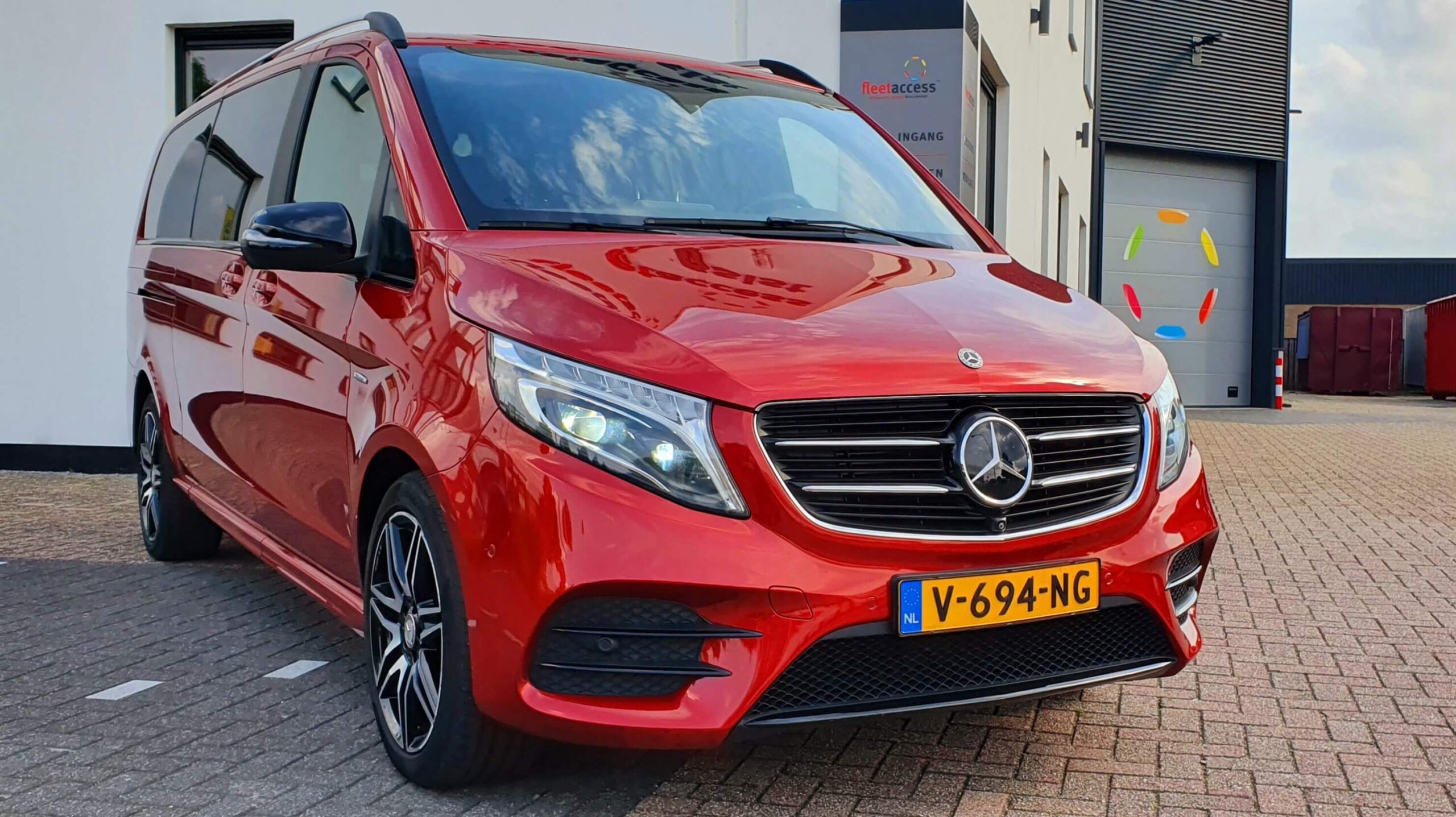A red Mercedes-Benz V-Class parked in front of the entry of the building of Fleetaccess B.V. Alarm systems in Nuenen, the Netherlands