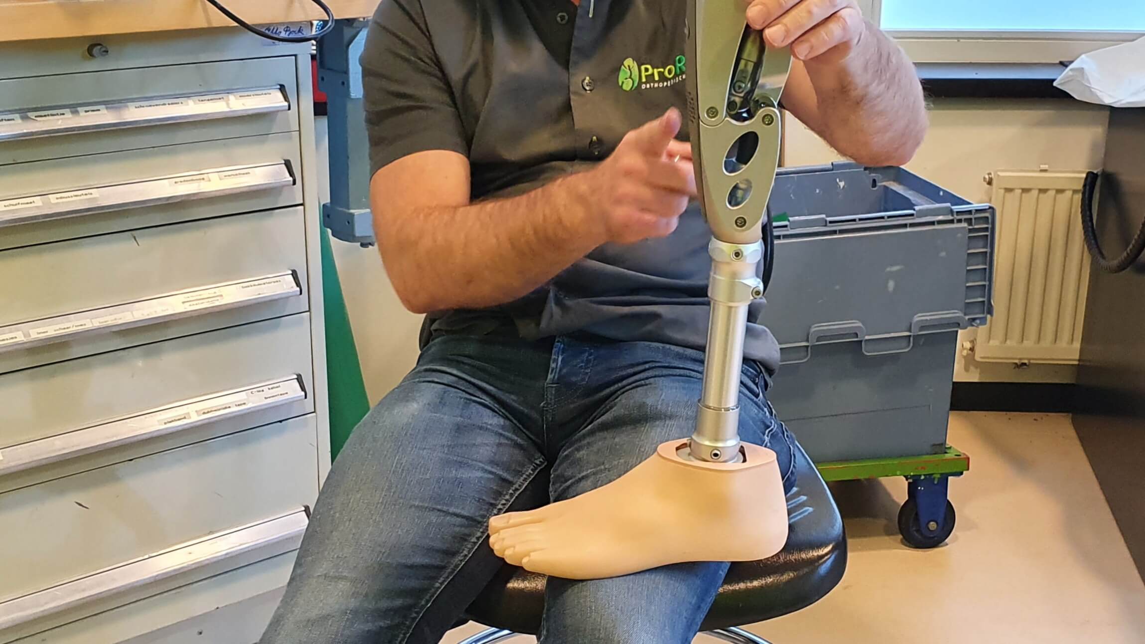 afbeelding van een prothese waarbij de orthopedisch instrumentmaker van proreva uitleg geeft als voorbereiding van een amputatie. De prothesemaker is een man waardoor er geen genderverschil met de patiënt is.