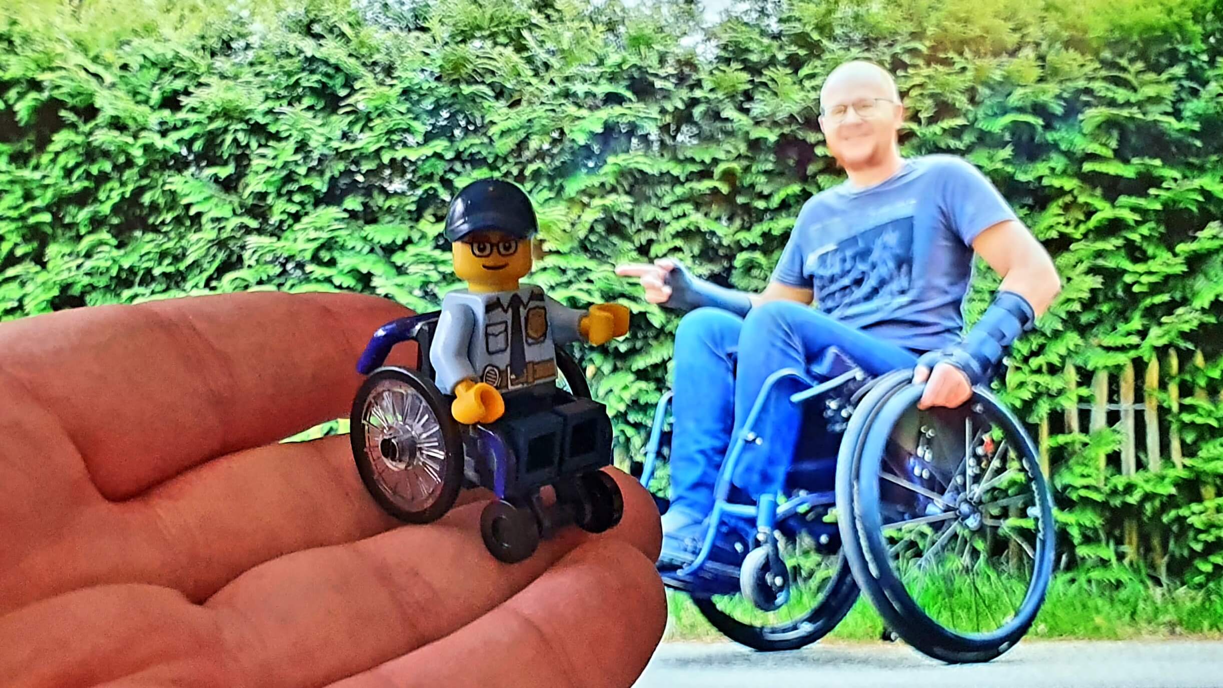 afbeelding van een SigFig LEGO poppetje in rolstoeltje en uniform met op de achtergrond een man in een rolstoel
