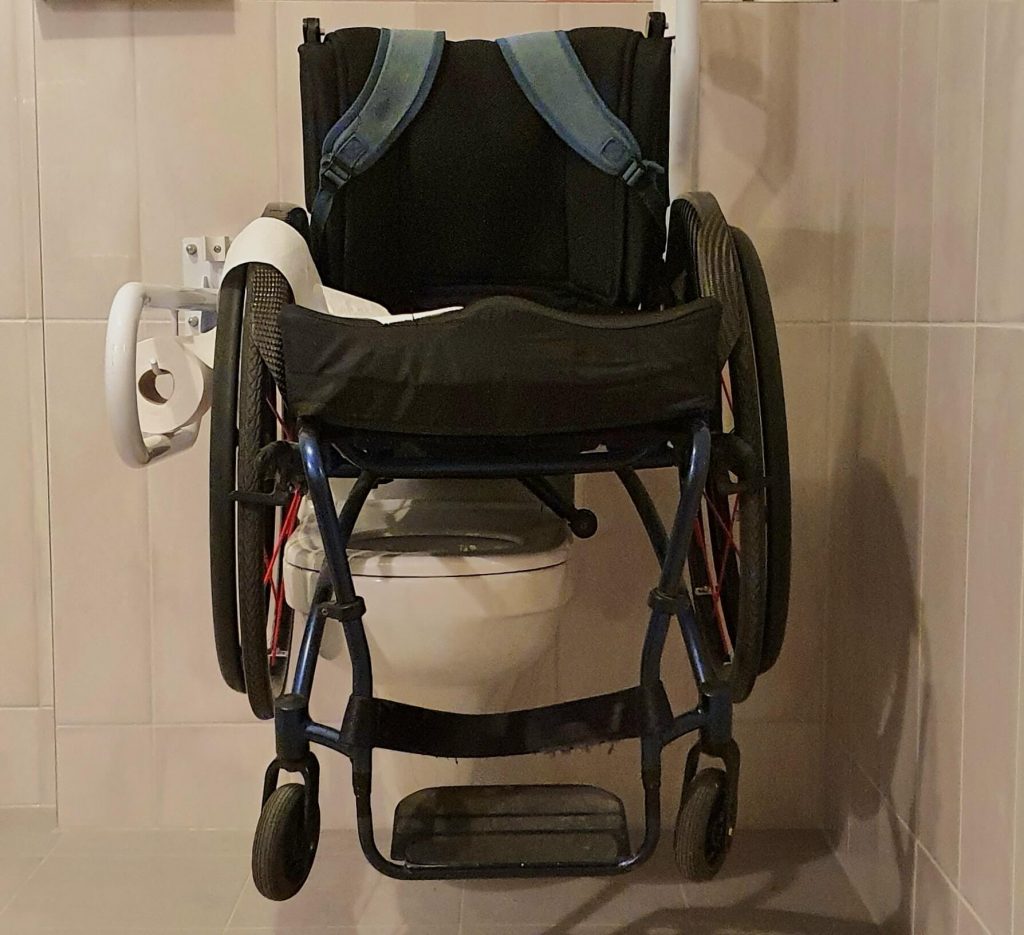 Foto van een rolstoel bovenop een toilet met daarnaast toiletbeugels ter illustratie van hoe McDonald's Meerkerk denkt dat mensen met een beperking naar het toilet gaan