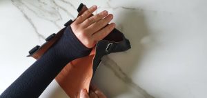 afbeelding van een hand met reuma die in een pols-hand-brace, oftewel orthese of spalk, gestoken wordt