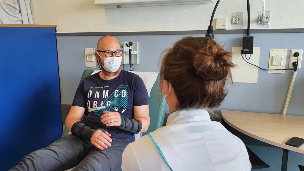 Foto van een mannelijke patiënt die een gesprek voert over zijn hulpvraag met een vrouwelijke arts als zorgverlener.