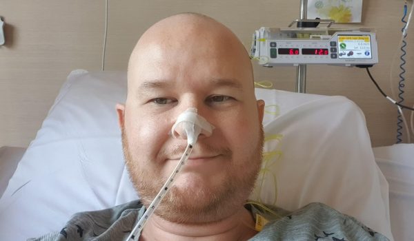 Foto van een kale man met baard die in een ziekenhuisbed ligt en een maaghevel of neussonde heeft in zijn neus na de aanleg van een stoma, behorend tot de blogs van RaGaStoma