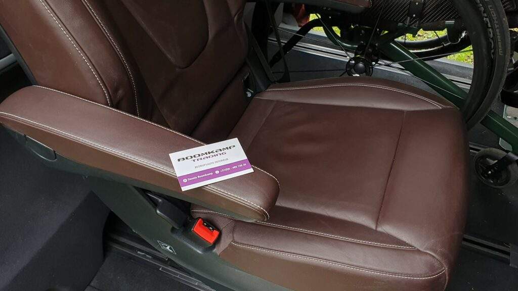 Close-up van een maron bruin leren Mercedes-Benz V-Klasse stoel met op de armleuning een kaartje van Boomkamp Trading.