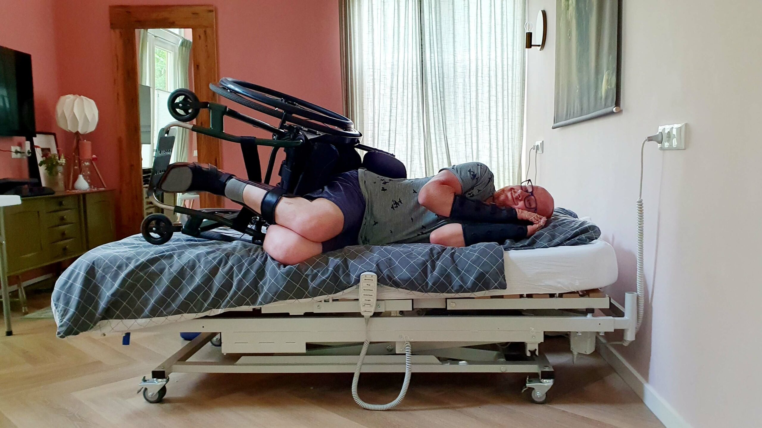 Foto van een man die in zijn rolstoel in bed ligt ter illustratie van de blog FAQ over leven met een handicap, omdat geregeld gevraagd wordt je met een beperking ook slaapt in een rolstoel of met je hulpmiddelen aan of om, zoals met spalken, orthesen of silversplints.