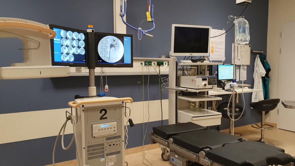 foto van een behandelruimte in het ziekenhuis met een röntgenapparaat en foto's op de beeldschermen van nieren met contrastvloeistof. Dit is niet de operatiekamer waar de stomarevisie plaats vond met de gratis buikwandcorrectie.