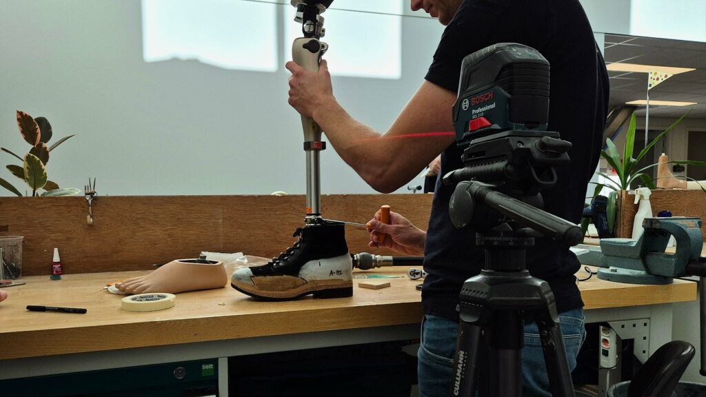 Een prothesemaker is een Kenevo computergestuurde AAK protheseknie aan het uitlijnen op een beenprothese van iemand met een bovenbeenamputatie. De uitlijning doet de prothesedeskundige met een kruislijnlaser van Bosch.