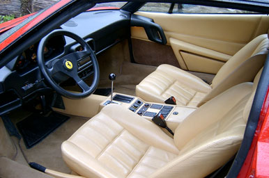 Interieurfoto van een Ferrari 328 GTS. De stoelen en middenconsole zijn bekleed met beige leer. Het dashboard en het stuur is bekleed met zwart leer.