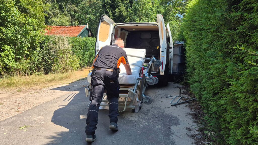 Een flexobed verzorgingsbed wordt opgehaald door de leverancier en ingeladen achterin een busje.